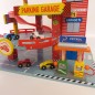 Preview: Spielzeug-Garage mit einem rot-weiß gestreiften Aufzugsschacht, einer Zapfsäule an der Seite und mehreren bunten Holzautos auf den Fahrbahnen
