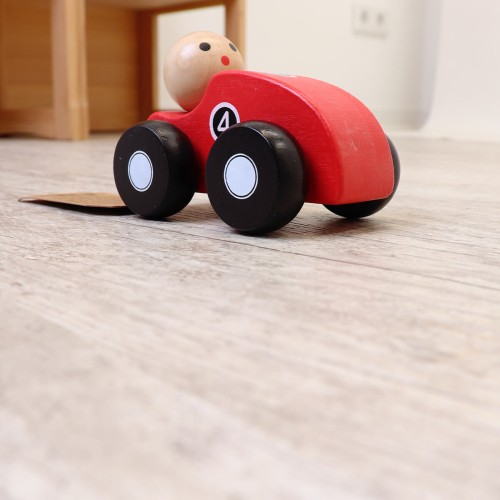 Spielzeugauto mit Männchen fährt in Zimmer