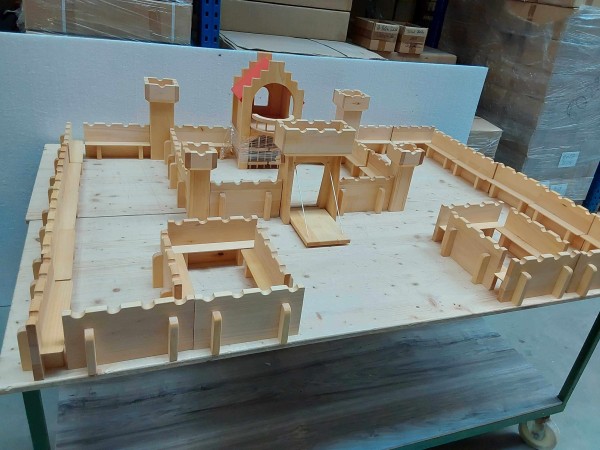 Große Spielzeugburg aus geöltem Lindenholz mit zahlreichen Mauerteilen, Türmen und einem zentralen Torbau