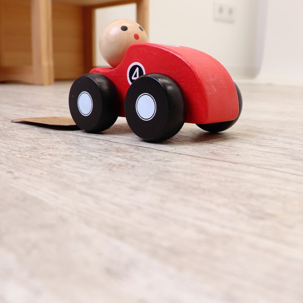 Spielzeugauto mit Männchen fährt in Zimmer