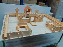 Große Spielzeugburg aus geöltem Lindenholz mit zahlreichen Mauerteilen, Türmen und einem zentralen Torbau